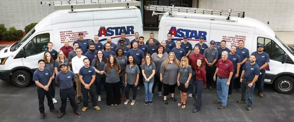 A group of employees in uniform stand in front of two company vans with "ASTAR" logos.