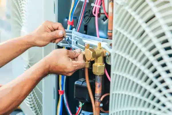 Person fixing HVAC system with tools and wires visible.